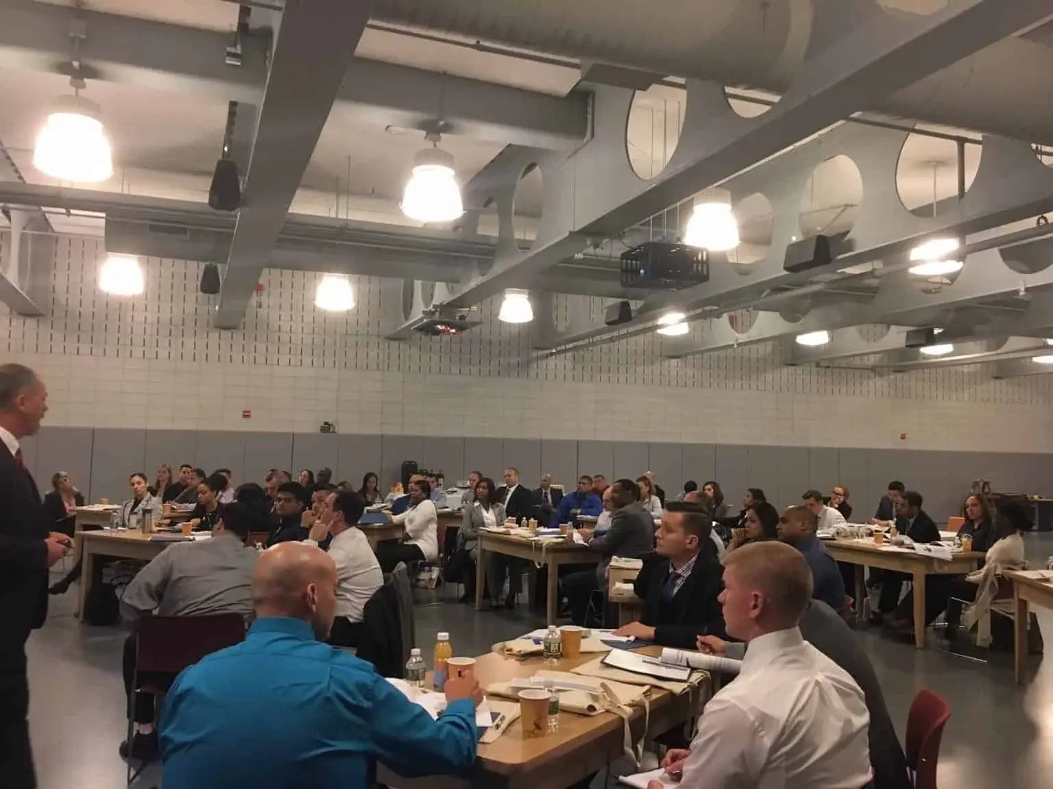 A group of people seated at tables in a classroom